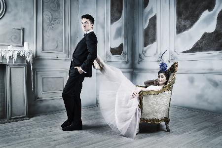 melancholy. man stands in the loft leaning on the legs of a ballerina sitting in an armchair